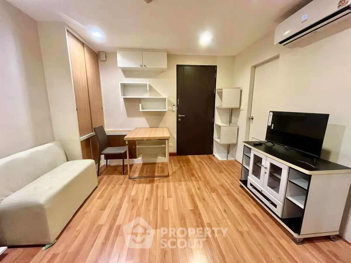 Modern living room with wooden flooring, sleek furniture, and air conditioning unit.