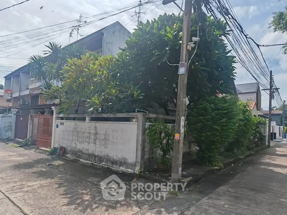 Charming corner property with lush greenery and privacy wall in a serene neighborhood.
