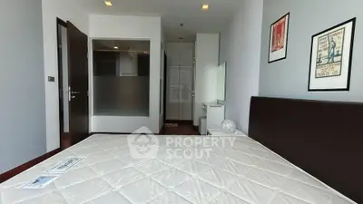 Spacious bedroom with modern decor and ample natural light, featuring a large bed and stylish wall art.