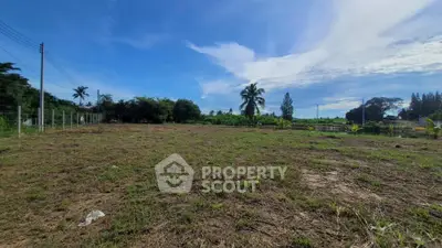 Expansive vacant land with lush greenery and clear blue sky, perfect for development opportunities.