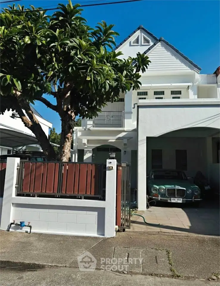 Charming two-story house with a garage and lush tree in front yard