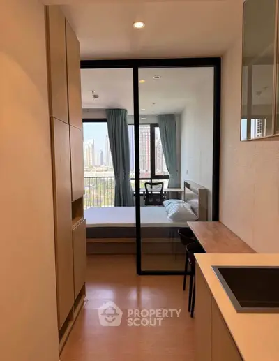 Modern studio apartment with open layout and city view, featuring sleek kitchen and cozy bedroom area.