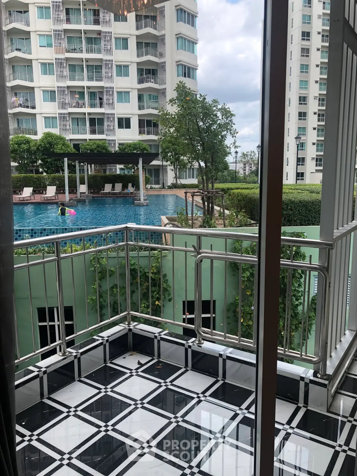 Charming balcony view overlooking a serene pool in a modern residential complex.