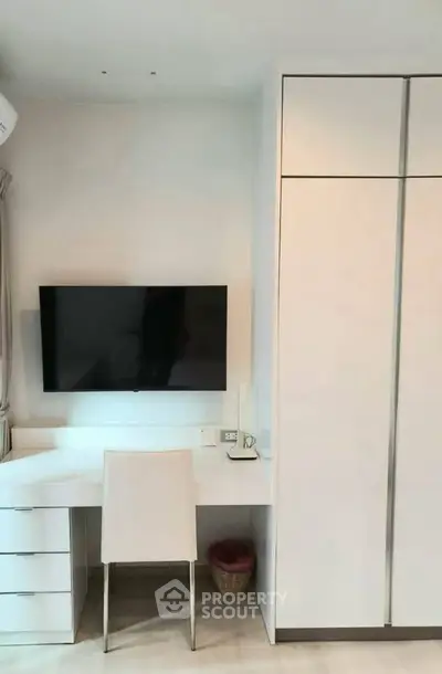 Modern study area with sleek desk, wall-mounted TV, and spacious wardrobe in a minimalist design.