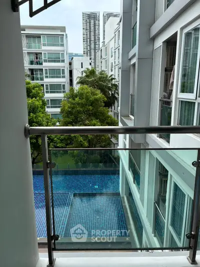 Modern apartment balcony with pool view and lush greenery