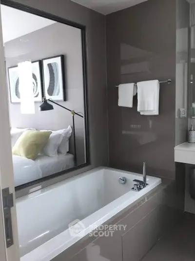 Modern bathroom with sleek bathtub and view into stylish bedroom