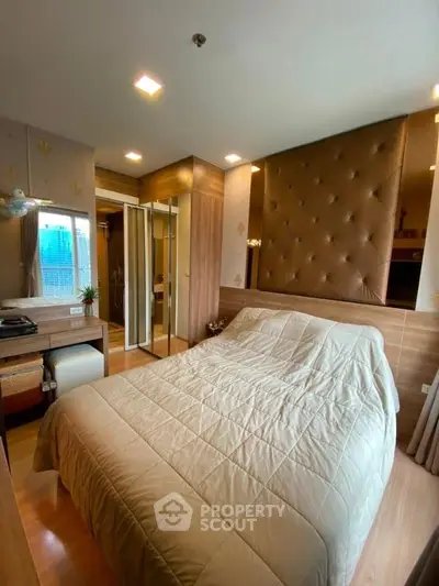Cozy bedroom with modern decor and ample natural light, featuring a stylish padded headboard and mirrored wardrobe.