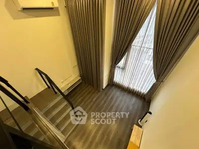 Modern loft-style living room with high ceilings and large windows