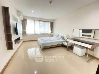 Spacious bedroom with modern decor and natural light in a stylish apartment.