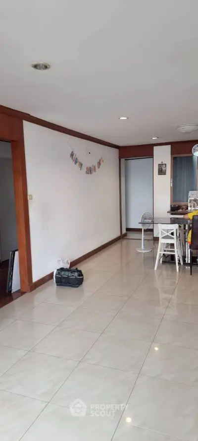 Spacious living area with tiled flooring and wooden accents, perfect for family gatherings.