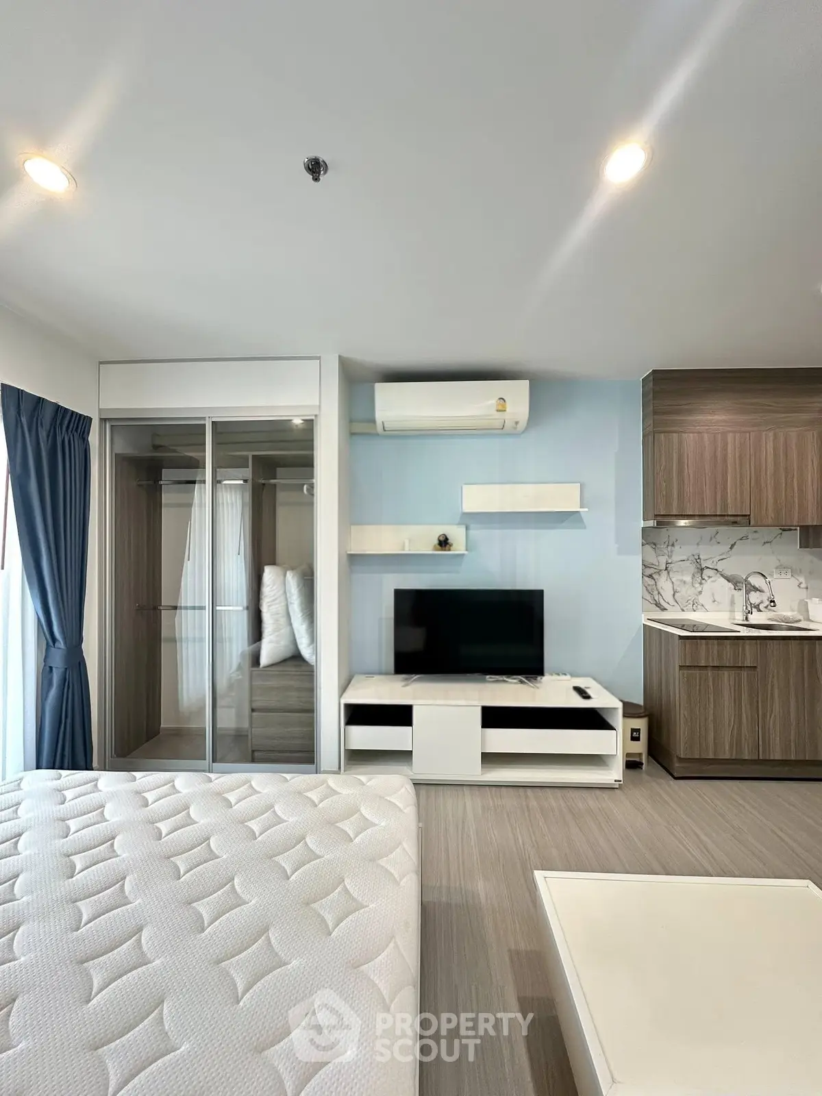Modern studio apartment with sleek design, featuring a cozy living area, built-in wardrobe, and compact kitchen.