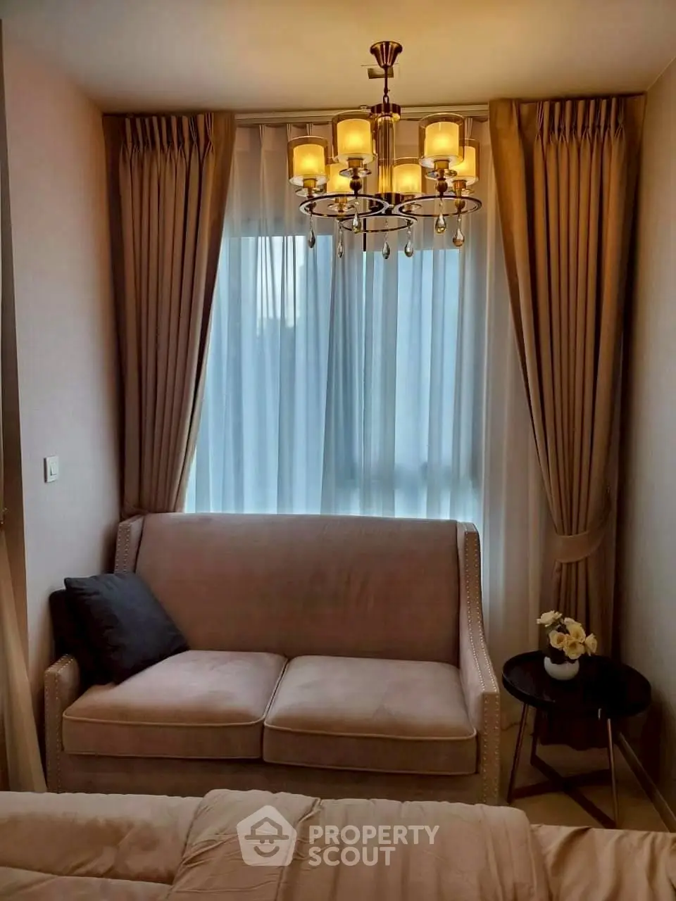 Cozy living room with elegant chandelier and plush sofa in modern apartment.