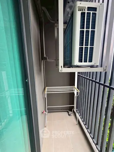 Compact balcony with air conditioning unit and drying rack, ideal for urban living.