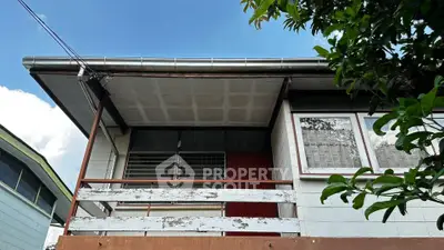 Charming vintage home exterior with rustic balcony and lush greenery, perfect for renovation enthusiasts.