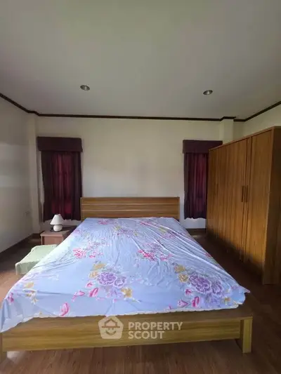 Spacious bedroom with wooden furniture and floral bedding