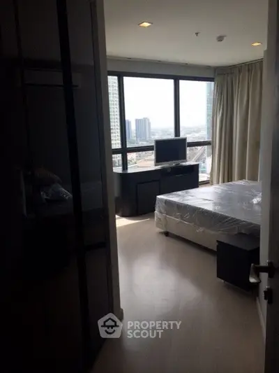 Modern bedroom with large windows offering stunning city views in a high-rise apartment.