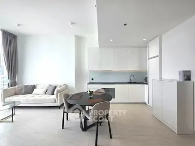 Modern open-plan living room and kitchen with sleek white cabinetry and cozy seating area.