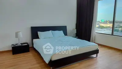 Spacious bedroom with large window and modern furnishings