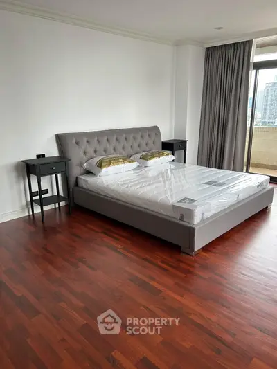 Spacious bedroom with elegant hardwood floors and city view balcony access.