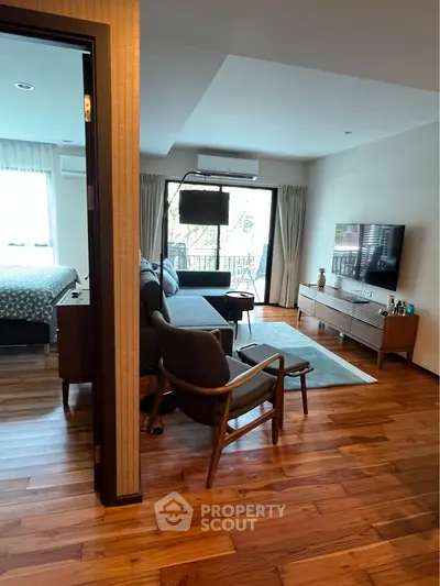 Spacious living room with modern decor and wooden flooring, featuring a cozy seating area and large TV.