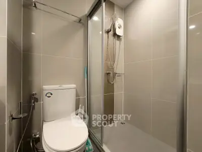 Modern bathroom with sleek shower and toilet in neutral tones.