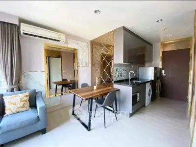 Modern open-layout living room with stylish kitchen and dining area, featuring sleek appliances and elegant decor.