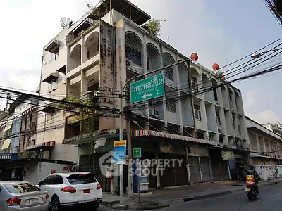 Urban street view of a multi-story building with retail space in bustling city area.