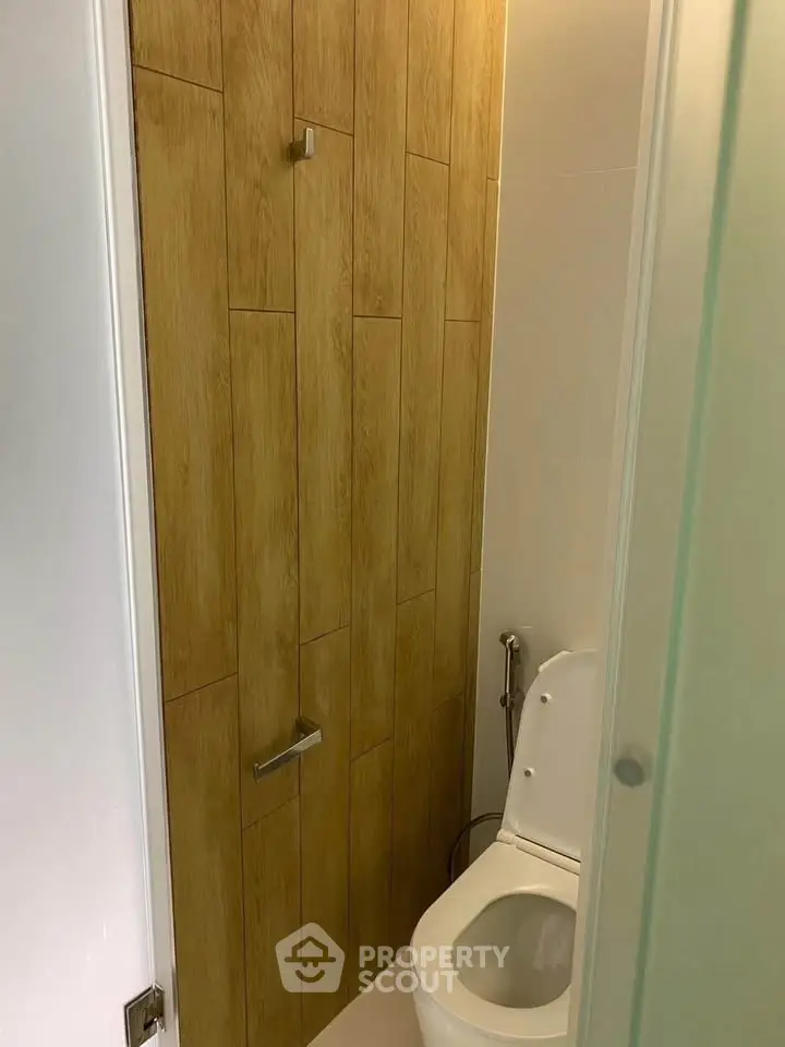 Modern bathroom with wooden accent wall and sleek toilet design.