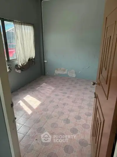 Spacious empty room with tiled floor and natural light, ideal for customization.