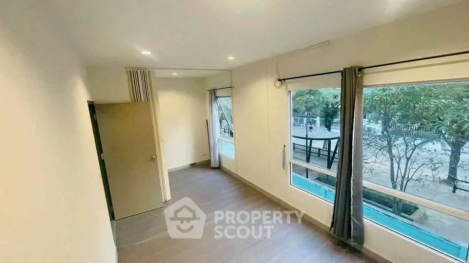 Spacious room with large windows offering a serene garden view, perfect for a tranquil living space.