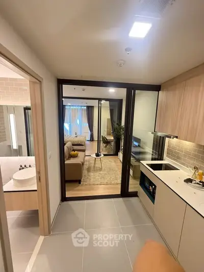 Modern apartment interior with open kitchen and cozy living room, featuring stylish decor and natural lighting.