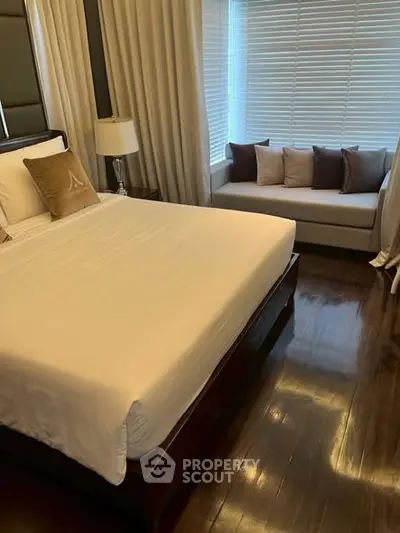 Elegant bedroom with polished wooden floors and cozy window seating area.