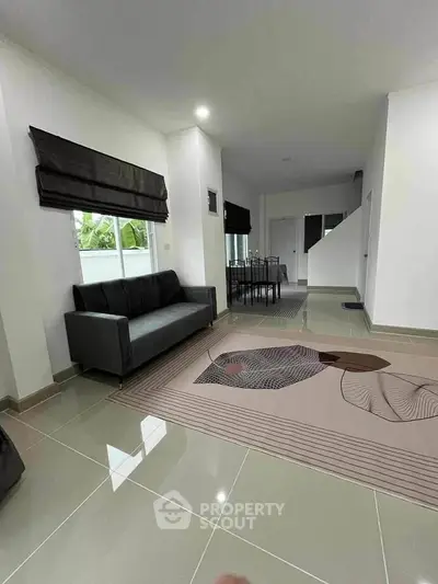 Modern living room with sleek sofa and artistic rug in a bright, open space.