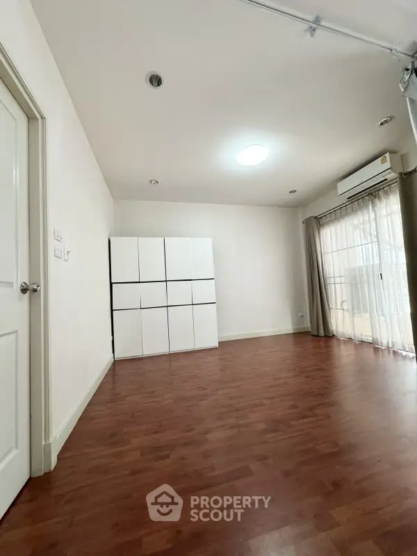 Spacious room with wooden flooring and ample natural light, ideal for versatile use.
