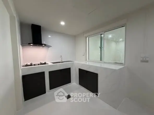 Modern kitchen with sleek black cabinets and gas stove in a minimalist design.