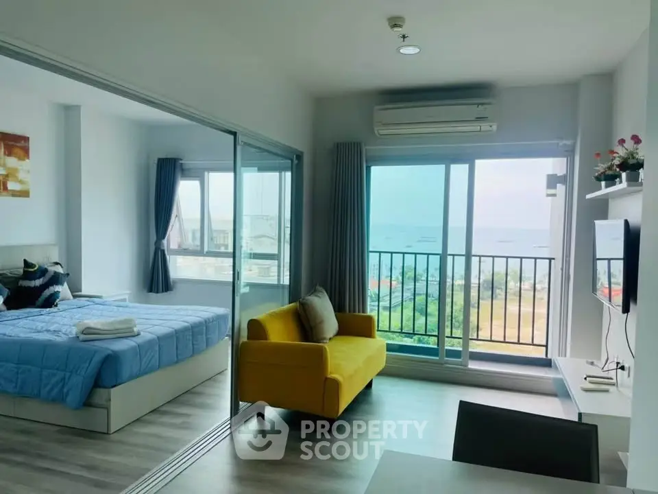 Modern apartment with ocean view, featuring a cozy living room and bedroom with large windows.