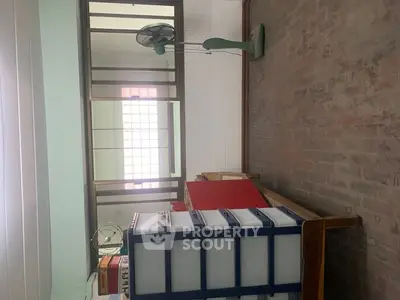 Cozy room with brick flooring and vintage fan, ideal for creative workspace or storage.