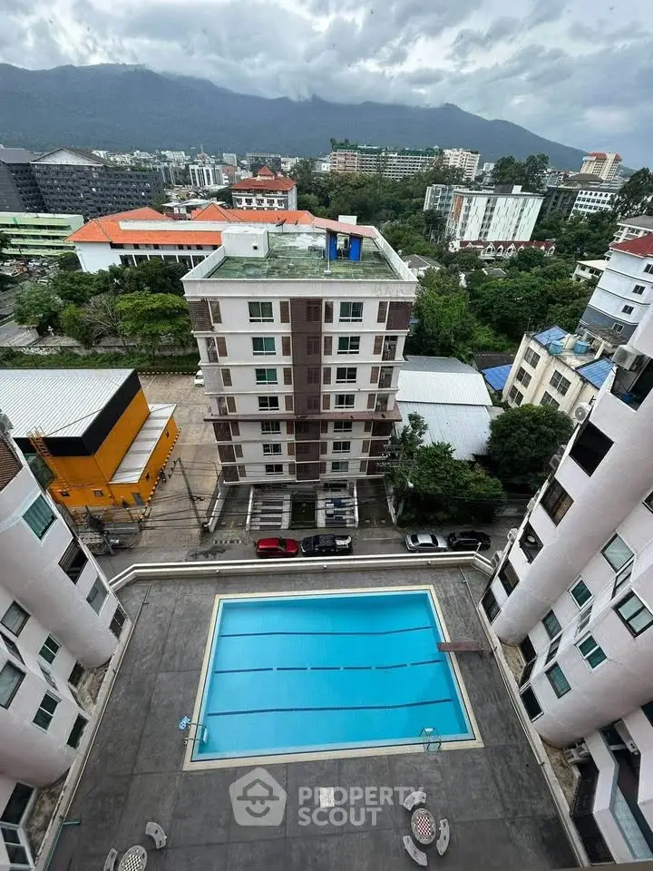 Stunning aerial view of modern apartment complex with pool and mountain backdrop.