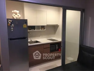 Modern compact kitchen with sleek cabinetry and built-in appliances in a cozy apartment.