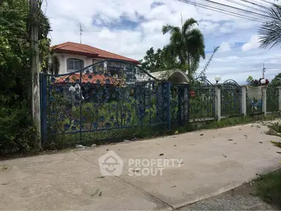 Charming gated property with lush greenery and red-tiled roof in a serene neighborhood.