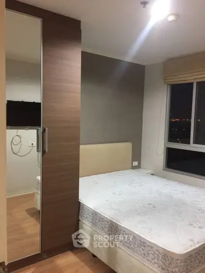 Cozy bedroom with modern decor and city view window, perfect for urban living.