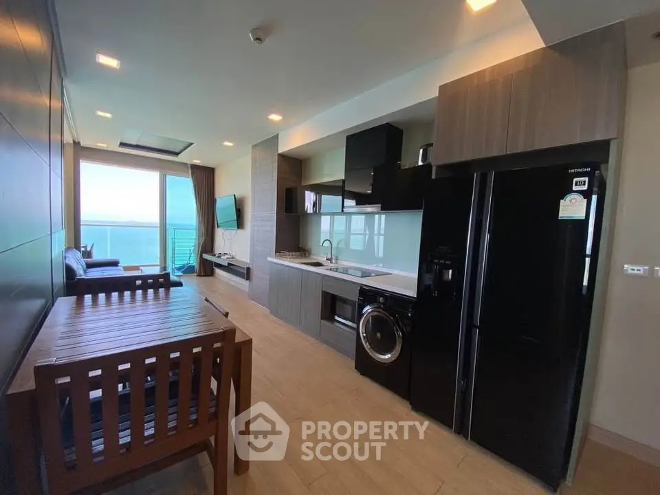 Modern open-layout kitchen with ocean view and sleek appliances in a stylish apartment.