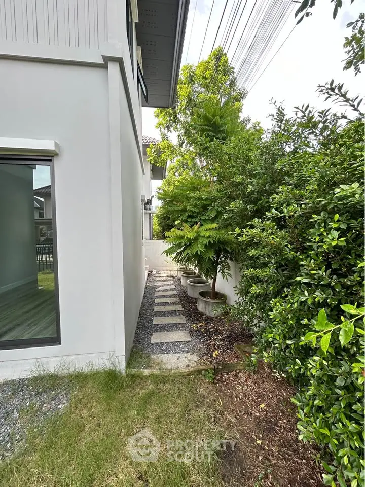 Charming side garden pathway beside modern house with lush greenery