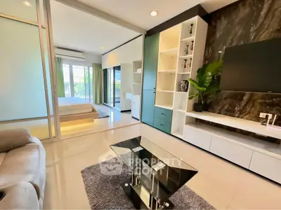 Modern open-plan living room with sleek furniture and a view into a stylish bedroom.