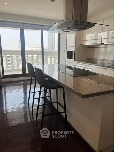 Modern kitchen with open layout and city view, featuring sleek countertops and high chairs.