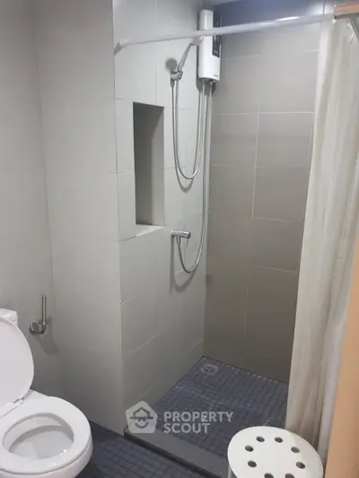 Modern bathroom with shower and toilet in sleek gray tiles.
