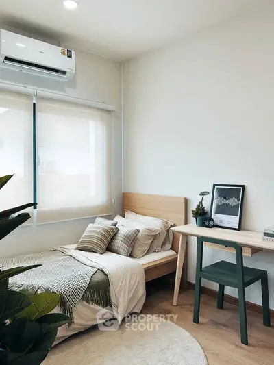 Cozy bedroom with modern decor and natural light, featuring a stylish desk and comfortable bed.