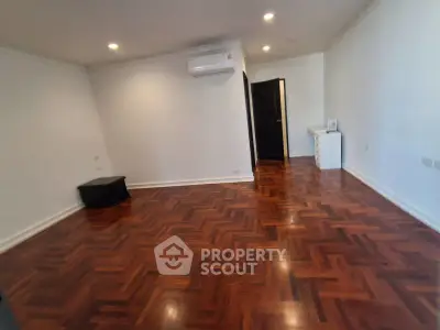 Spacious living room with elegant wooden flooring and modern air conditioning unit.