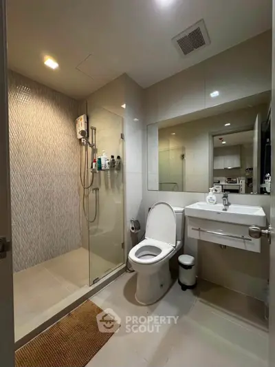 Modern bathroom with glass shower and sleek fixtures in contemporary apartment.