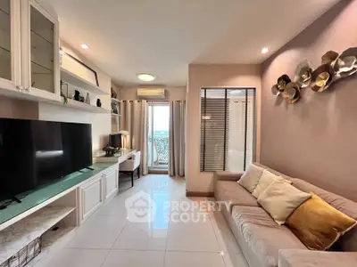 Modern living room with stylish decor and large TV, featuring a cozy sofa and bright natural light.